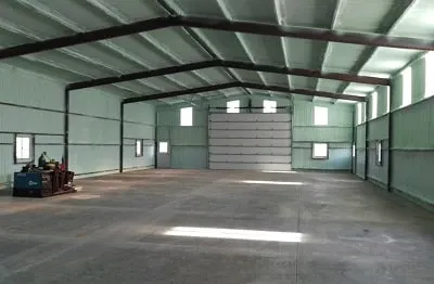 Interior of a commercial metal building with exposed steel roof framing and an overhead door